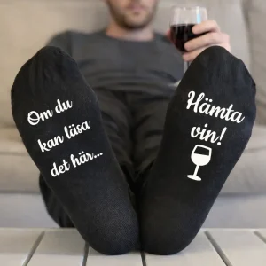 Svarta strumpor med texten ”Om du kan läsa det här… Hämta vin!” i vitt tryck